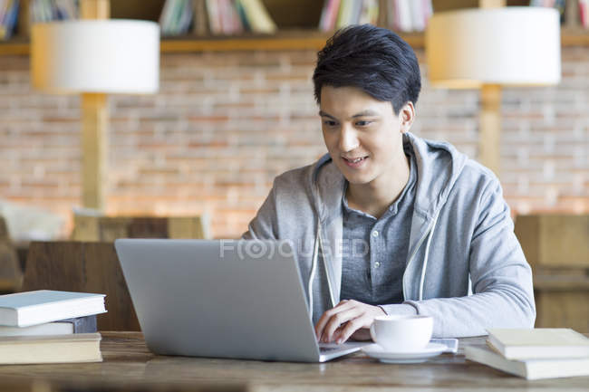 Chinois mâle étudiant en utilisant un ordinateur portable dans le café — Photo de stock