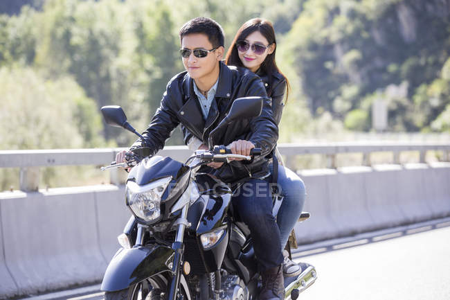 Chinese couple riding motorcycle together — Stock Photo