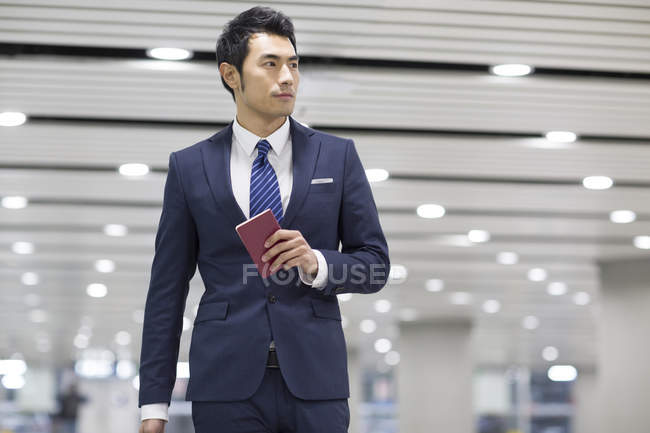 Chinese businessman holding passport in airport — Stock Photo