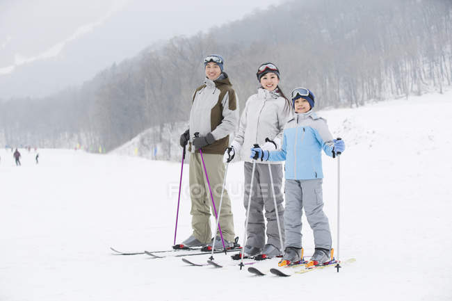 Chinese parents with son posing on snowy slope — Stock Photo