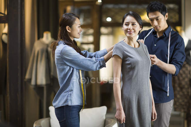Stilisti cinesi regolando abito cliente femminile — Foto stock