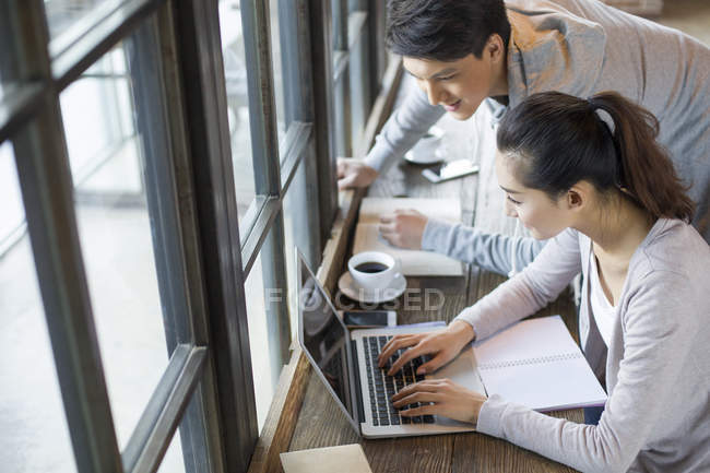 Uomo e donna cinese che utilizzano il computer portatile in caffè — Foto stock