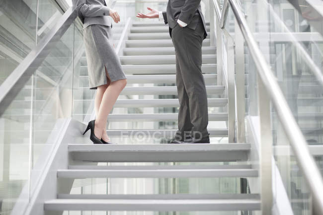 Китайские бизнесмены разговаривают на лестнице — стоковое фото