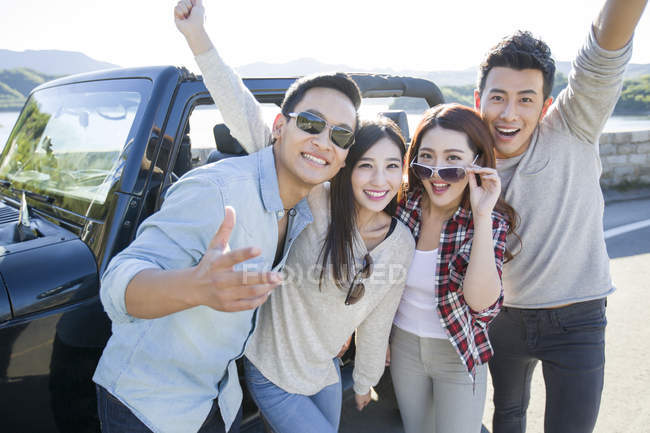 Китайские друзья позируют с машиной в пригороде — стоковое фото