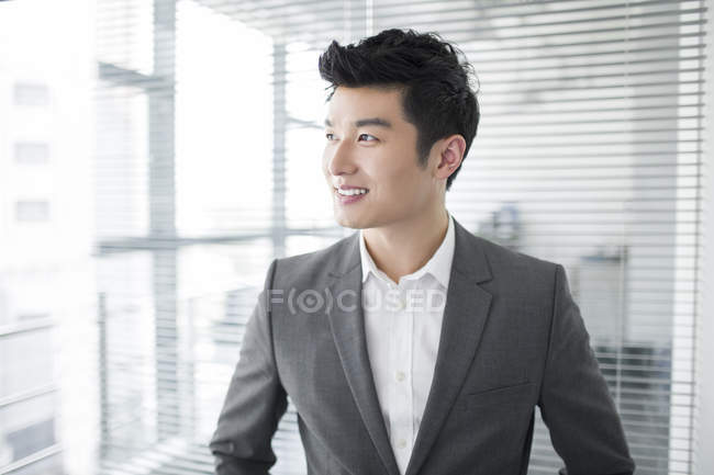 Uomo d'affari cinese guardando attraverso la finestra in ufficio — Foto stock