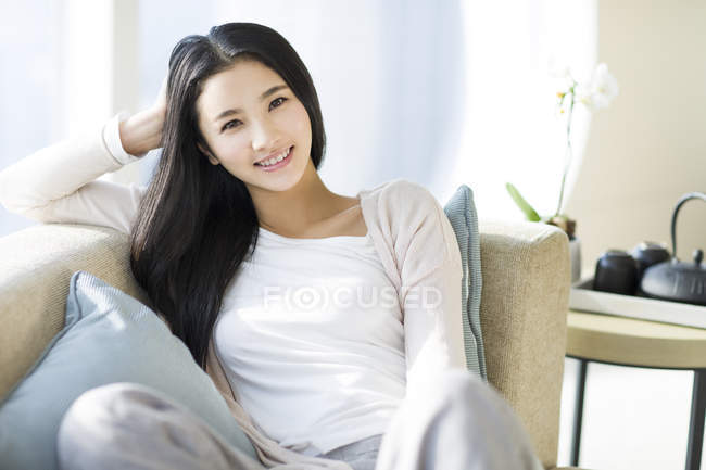 Retrato De Mujer China Sentada En El Sofá En El Interior Del Hogar — Hembra Ropa Casual Stock