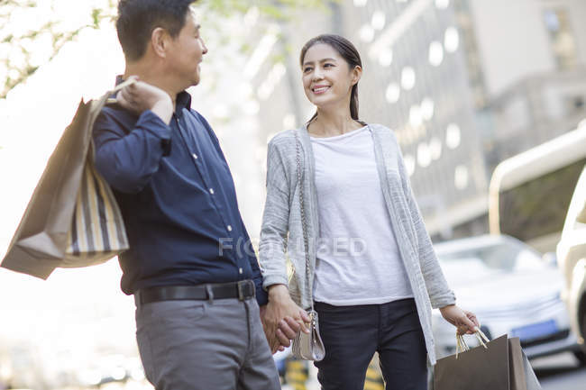 Mature chinese couple with shopping bags in city — Stock Photo