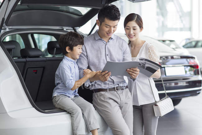 Chinese family looking into car catalog in showroom — Stock Photo