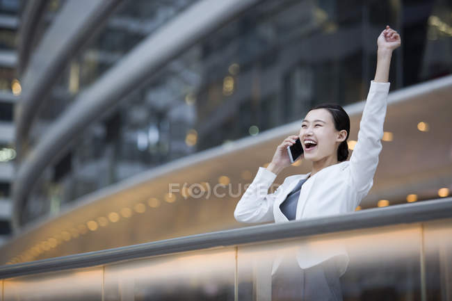 Femme d'affaires chinoise parlant au téléphone et acclamant — Photo de stock