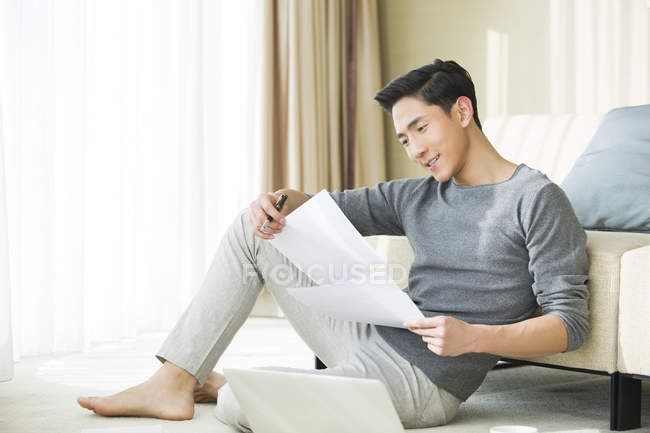 Uomo cinese che lavora con i documenti a casa — Foto stock