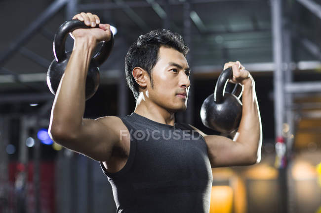 Chinese man training with kettlebells in crossfit gym — Stock Photo