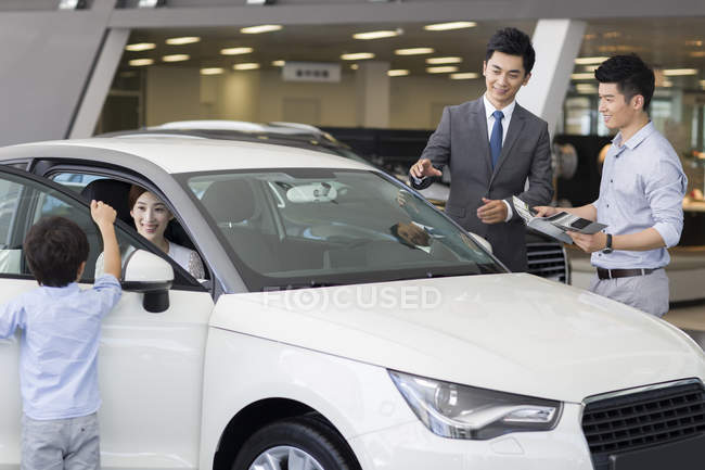 Chinese car dealer helping family choosing car in showroom — Stock Photo