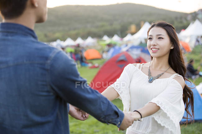 Happy chinese couple holding hands at music festival lawn — Stock Photo