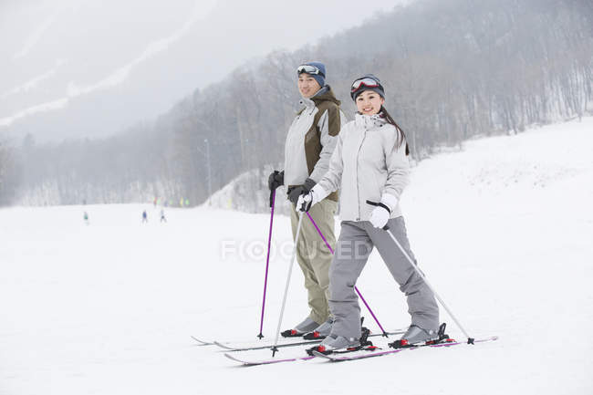 Chinesisches Paar steht im Skigebiet auf Schnee — Stockfoto