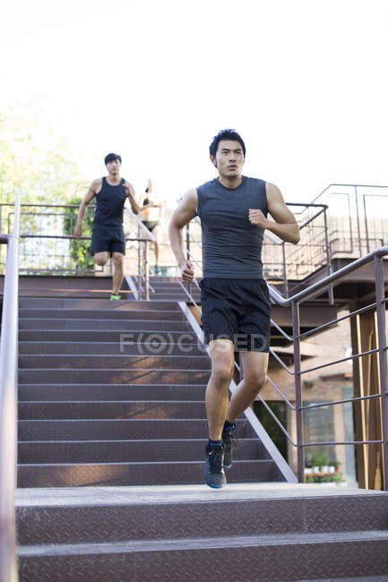Male joggers running down street stairs — Stock Photo