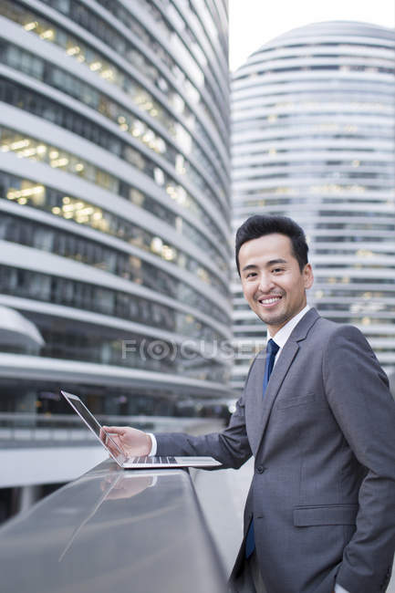 Китайский бизнесмен использует ноутбук в финансовом районе — стоковое фото