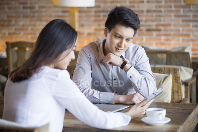 Chino hombre y mujer usando tableta digital en la cafetería - foto de stock