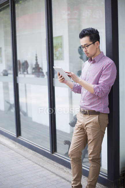 Chinese man using digital tablet on street — Stock Photo
