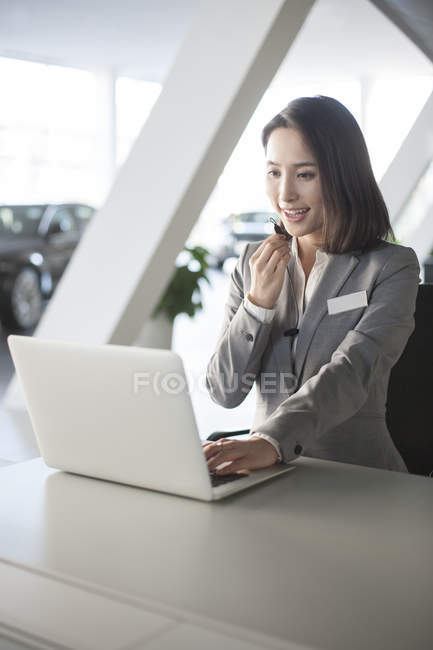 Chinese car saleswoman working with laptop — Stock Photo