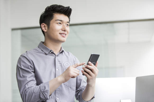 Uomo d'affari cinese utilizzando smartphone in ufficio — Foto stock