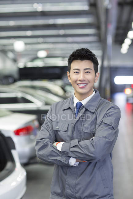 Chinese auto mechanic standing in workshop with arms folded — Stock Photo