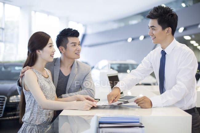 Casal chinês comprando carro no showroom — Fotografia de Stock