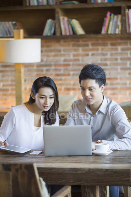 Chinese man and woman using laptop in cafe — Stock Photo