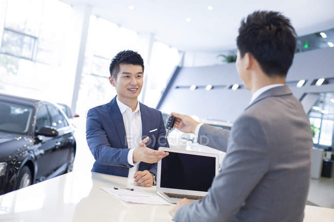 Chinesischer Autohändler gibt Mann Autoschlüssel in Showroom — Stockfoto