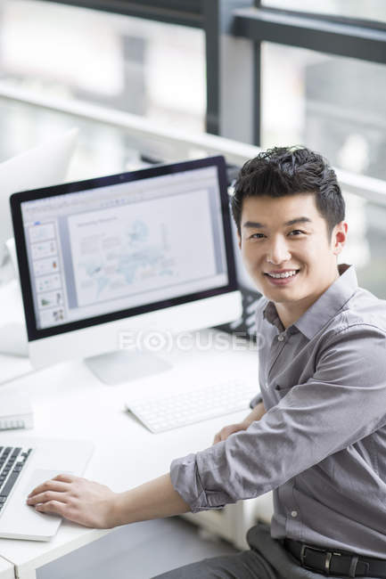 Chinese businessman sitting at workplace in office — Stock Photo