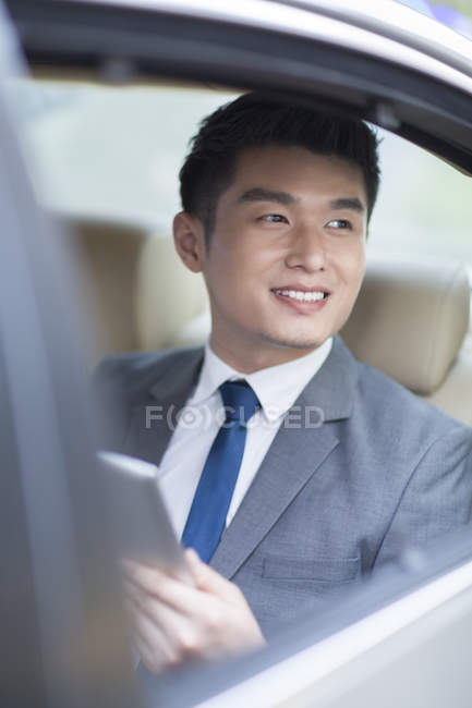 Homme d'affaires chinois assis sur le siège arrière de la voiture — Photo de stock