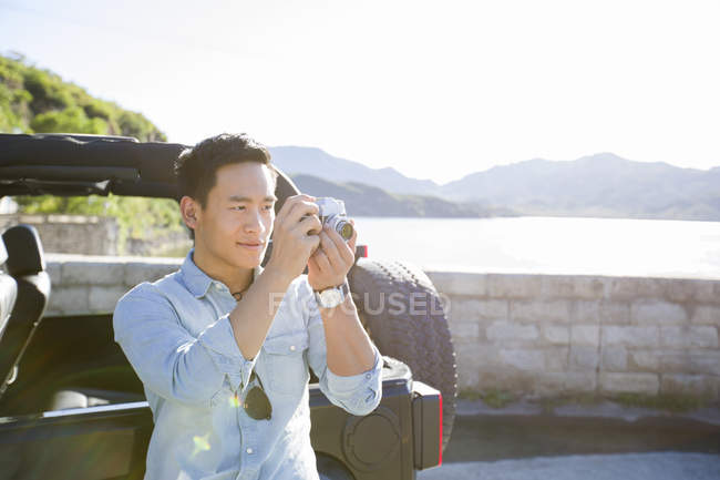 Chinese man taking photos at lakeside — Stock Photo