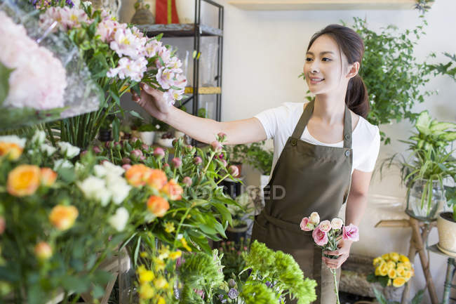 Floristería asiática femenina trabajando en floristería - foto de stock