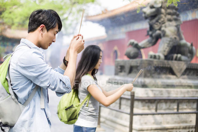 Chinese couple of tourists burning incense in Lama Temple — Stock Photo