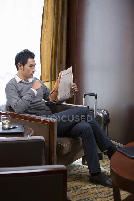 Uomo d'affari cinese che legge il giornale in camera d'albergo — Foto stock