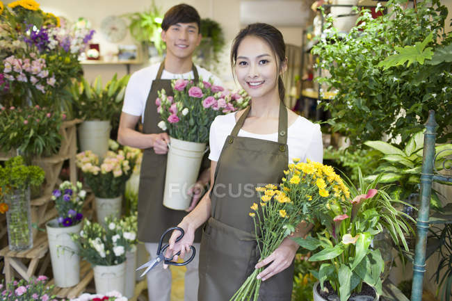 Chinese florists standing in flower shop with plants and scissors — Stock Photo