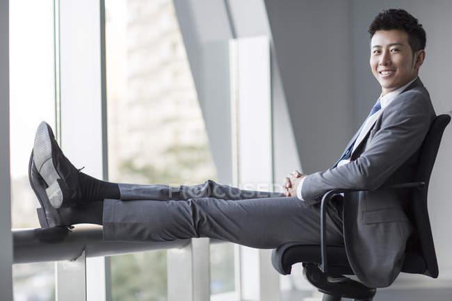 Uomo d'affari cinese seduto sulla sedia e guardando in macchina fotografica — Foto stock