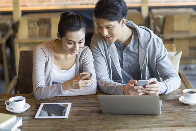 Chinese students using smartphone in cafe — Stock Photo