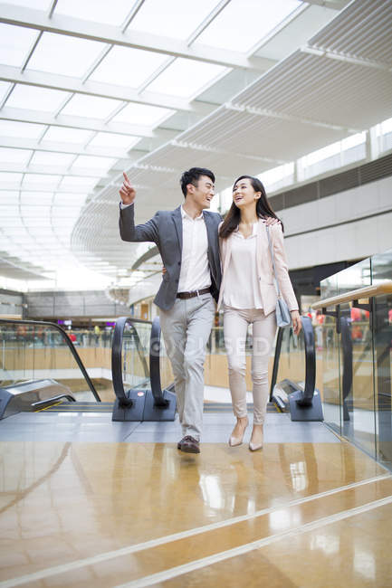 Chinese couple embracing while walking in shopping mall — Stock Photo
