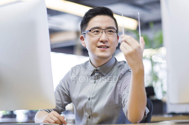 Китайський його працівник розвивається смартфон в офісі — стокове фото