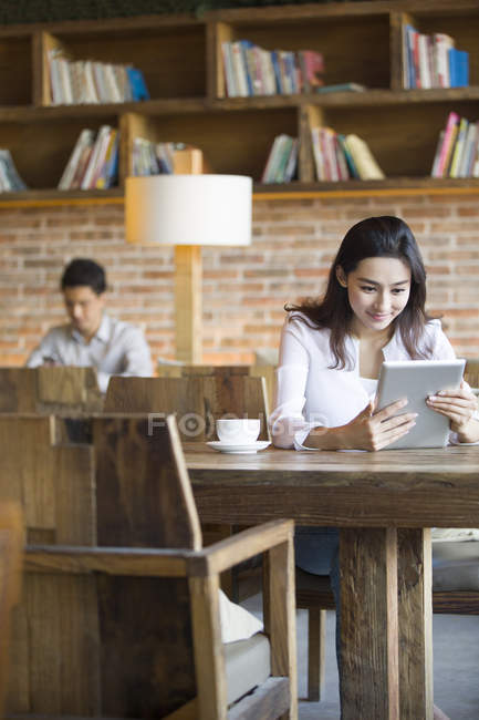 Mujer china usando tableta digital en la cafetería - foto de stock