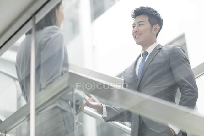 Chinese business people talking on stairs in office building — Stock Photo