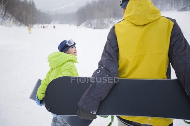 Pai e filho andando com snowboards na neve, close-up — Fotografia de Stock