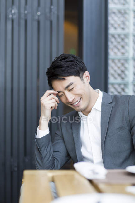 Hombre chino sentado y sonriendo en el restaurante - foto de stock