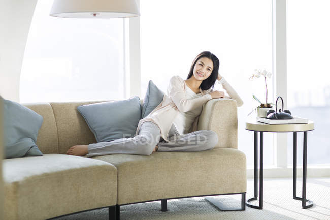 Chinês mulher sentada no sofá na sala de estar interior — Fotografia de Stock