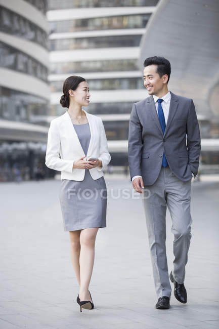 Chinese business people walking and talking on street — Stock Photo