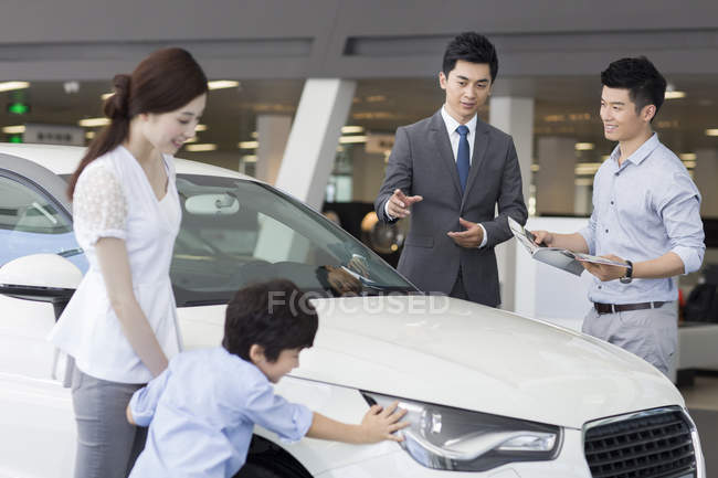 Chinese car dealer helping family choosing car in showroom — Stock Photo