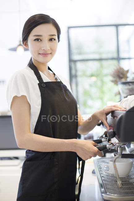 Barista chinês em pé na cafeteira e olhando na câmera — Fotografia de Stock