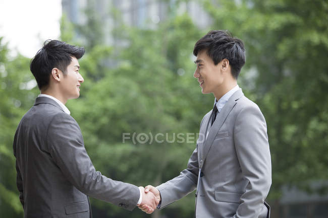 Chinese business person shaking hands on street — Stock Photo