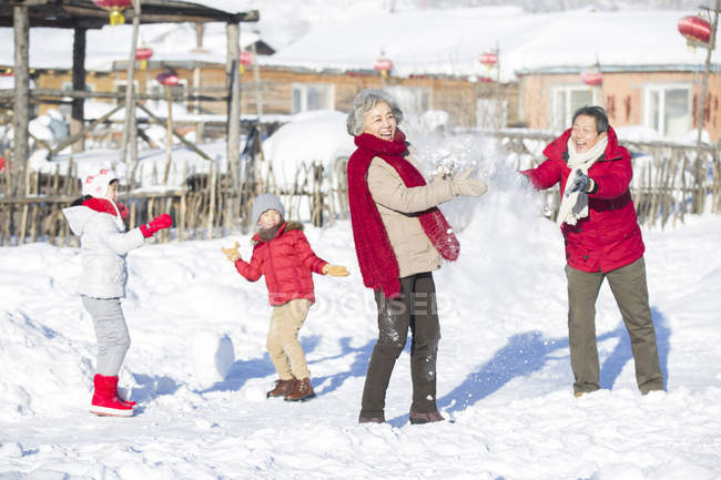 Chinese grandparents having snowball fight with children — Stock Photo