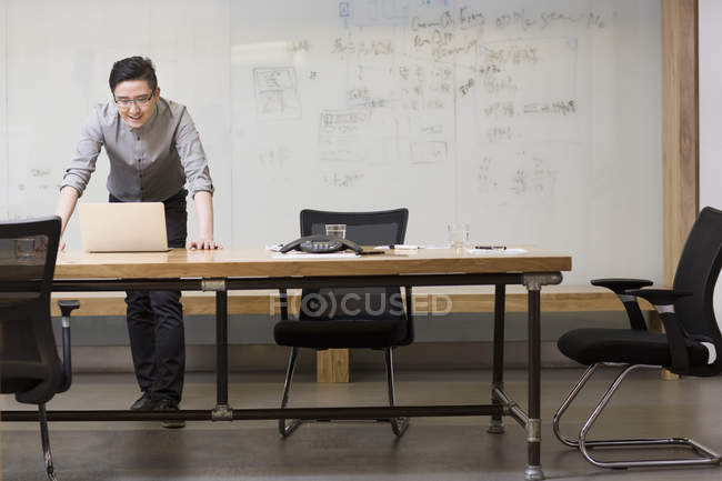 Chinese computer programmer using laptop in board room — Stock Photo